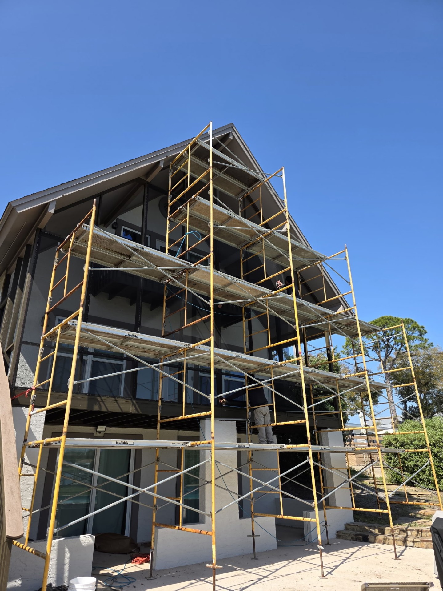A-frame home wrapped in scaffolding during exterior restoration